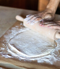 Cooking dough for pizza. The cook rolls out the dough and sips the flour