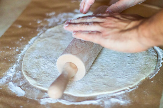 Cooking Dough For Pizza. The Cook Rolls Out The Dough And Sips The Flour