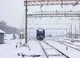 Railway train carriage resting on the tracks during snowfall on a winter day.