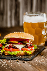 Fresh appetite homemade beef burger on stone board with glass of beer. Selective focus. 