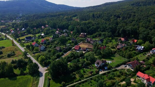 Mountain village and road with moving cars, aerial view. Beautiful mountain landscape with residential neighborhood and green fields. Countryside view