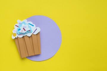 Birthday party. Paper cupcake on yellow background, top view with space for text