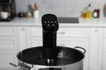 Pot with sous vide cooker in kitchen, closeup. Thermal immersion circulator