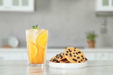 Tasty refreshing drink with orange and cookies on white marble table in kitchen - Powered by Adobe