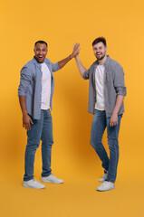 Men giving high five on yellow background