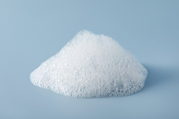 Drop of fluffy bath foam on light blue background