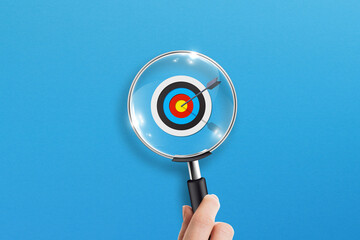 Business target concept with magnifying glass on blue background
