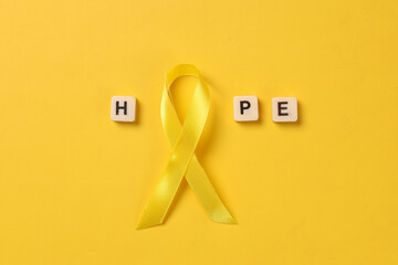 Word hope with yellow ribbon. Sarcoma Awareness, bone cancer, international childhood cancer day.  - obrazy, fototapety, plakaty