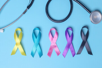 Colorful awareness ribbons with stethoscope on blue background. World cancer day. 