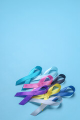 Colorful awareness ribbons stacked on blue background with copy space. World cancer day concept. 