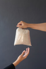 Hands giving and receiving rice for donation and charity on dark gray background. 
