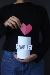 Hand holding heart shape to donation can for charity 