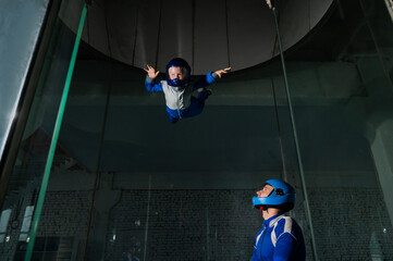 A man teaches a boy to fly in a wind tunnel. Lack of gravity.