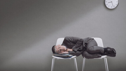 Exhausted businessman sleeping on chairs