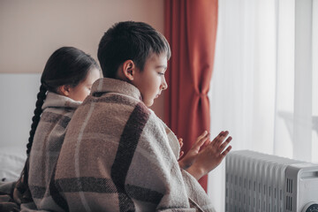 Shutdown of heating and electricity, blackout. Children warm their hands from a battery powered by...