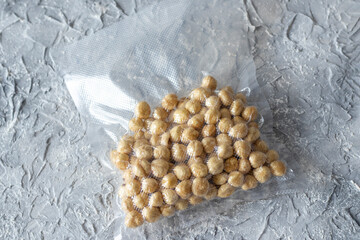 Hazelnuts in a plastic vacuum bag on a gray textured background.