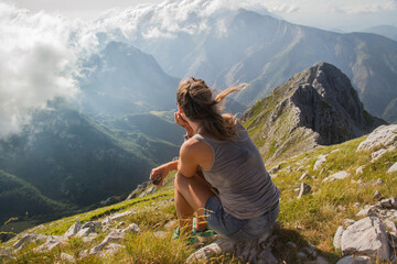 Mujer joven meditando en altas montañas cubiertas de nubes