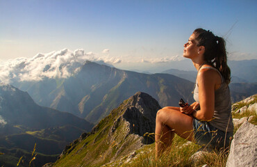 Naklejka na ściany i meble Mujer joven meditando en altas montañas cubiertas de nubes