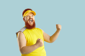 Fototapeta premium Happy guy having fun at sports workout. Funny athlete celebrating victory. Fat man in yellow sportswear fist pumping and shouting Yes, Yeah, I did it. Crazy coach supporting his team. Success concept