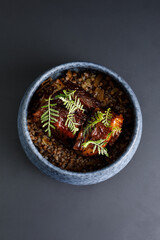 Grilled beef ribs served with buckwheat over black background