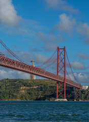 The "25 de Abril" suspension bridge (which translates to the "25th of April" Bridge) and the 'Cristo Rei' (which translates to "Christ the King") 
statue on the banks of the Tagus River in the capital
