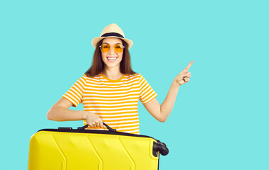 Happy cheerful beautiful young woman in sun glasses and panama hat holding travel bag, smiling and...