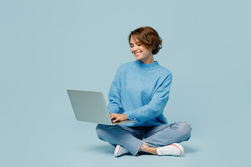 Full body young smiling happy fun cool IT woman wear knitted sweater hold use work on laptop pc...