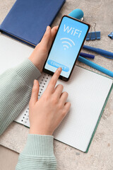 Woman holding mobile phone and connecting to WiFi zone on light background