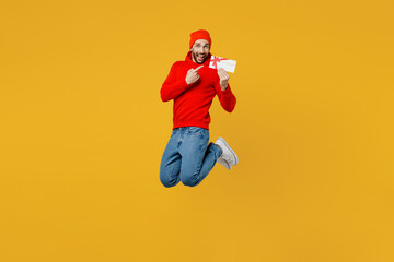 Obraz premium Full body young caucasian man wear red hoody hat hold point finger on gift certificate coupon voucher card for store isolated on plain yellow color background studio portrait People lifestyle concept
