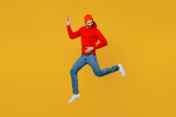 Fototapeta na wymiar Full body young musician fun caucasian man wear red hoody hat jump high pretend playing guitar doing hand gesture isolated on plain yellow color background studio portrait. People lifestyle concept.