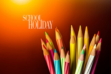Concept of School holiday  with inscription, color pencils on black background with flare. .