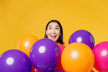 Fototapeta na wymiar Happy fun amazed surprised shocked impressed young woman wearing casual clothes celebrating near balloons look overhead on area isolated on plain yellow background Birthday 8 14 holiday party concept