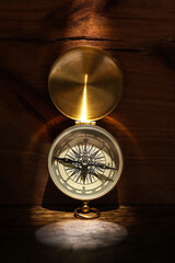 Golden compass on dark wooden background, top view