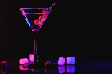 Martini cocktail drink splash with ice cubes in neon iridescent pink and blue colors. Minimal night...