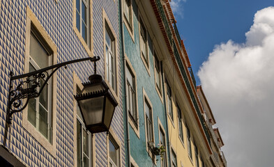 Fototapeta na wymiar The old, metal, street lamps mounted on colorful tiled buildings in Lisbon, Portugal 