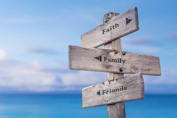 faith family friends text quote on wooden signpost crossroad by the sea