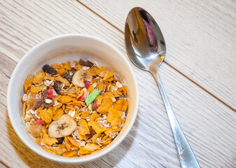 Healthy breakfast - cornflakes in a white bowl on a wooden table.