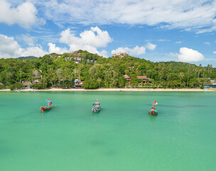 Fototapeta na wymiar Three traditional Thai boats on beach with turquoise waters