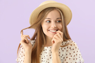 Young woman in hat biting nails on lilac background, closeup