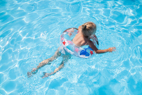 Blond girl swims with an inflatable ring in the pool. Top view, flat lay