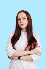 portrait of young attractive female doctor in white coat on blue background, copy space