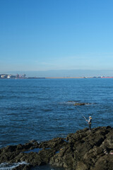 lonely fisherman stands and fishes with a fishing rod, catches fish on a rocky sea shore