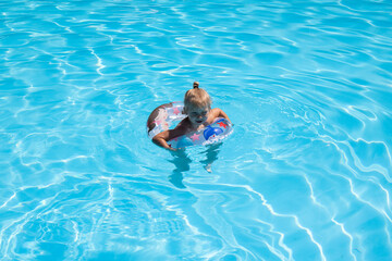 Child girl swims with an inflatable ring in the pool. Top view, flat lay