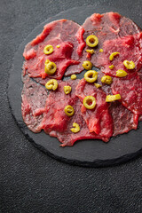 carpaccio spice meat raw appetizer olives, beef thin slices fresh healthy meal food snack on the...