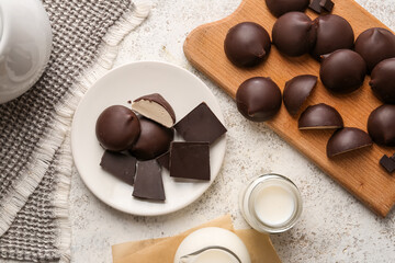 Plates with sweet chocolate bird's milk candies and jugs of milk on kitchen table