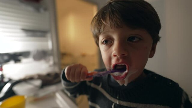 Child brushing teeth with toothbrush at night routine before bed. One small boy brushes dental hygiene in front bathroom mirror