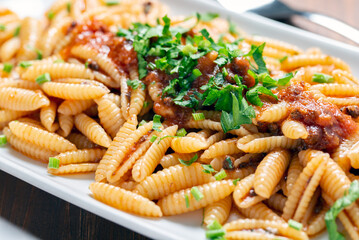 Piatto di deliziosi malloreddus, tipica pasta sarda condita con un saporito ragu di pesce, cibo italiano 