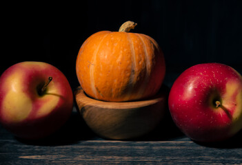 Pumpkin and apples on a black background.
