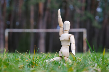 A wooden mannequin on the football gates background.  Football field in the pine woods.