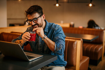 Portrait of a journalist stylish guy writing a story in a workplace in loft styled coworking, casually dressed in a denim shirt, sitting alone.